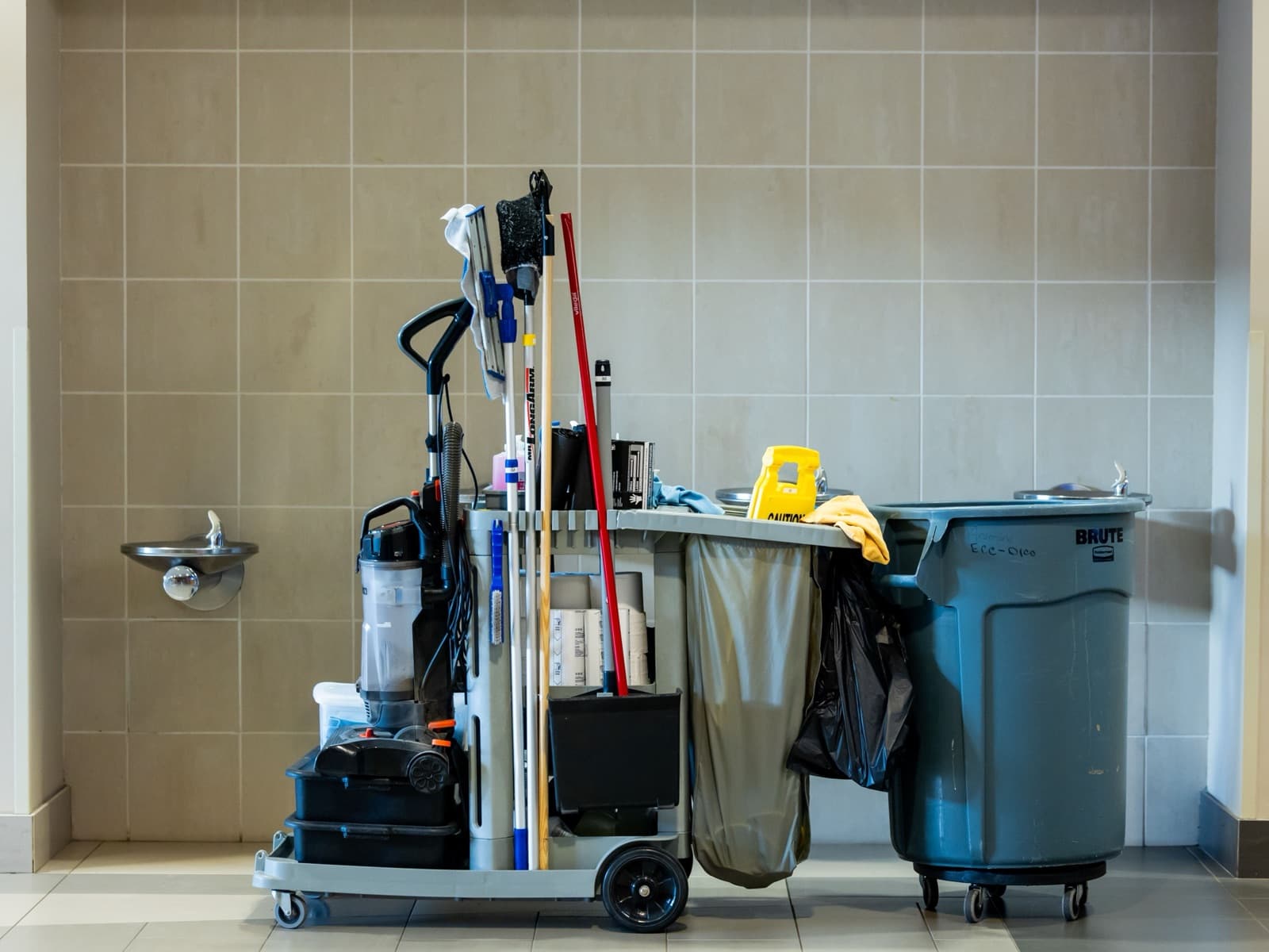 Schoonmaakwagen met materialen in een betegelde ruimte